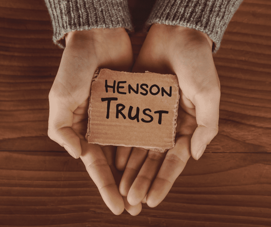 2 hands holding a piece of paper that says Henson Trust